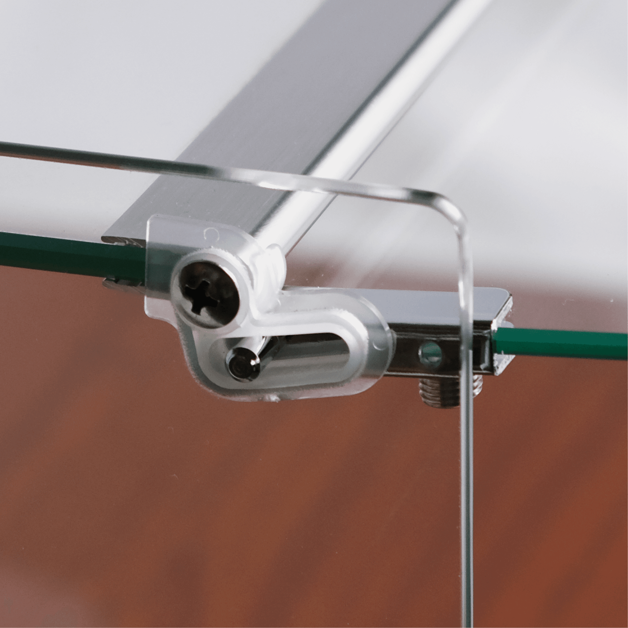 Close-up of curved clear glass panel attached with sleek metal bracket and hinge mechanism on walnut base.