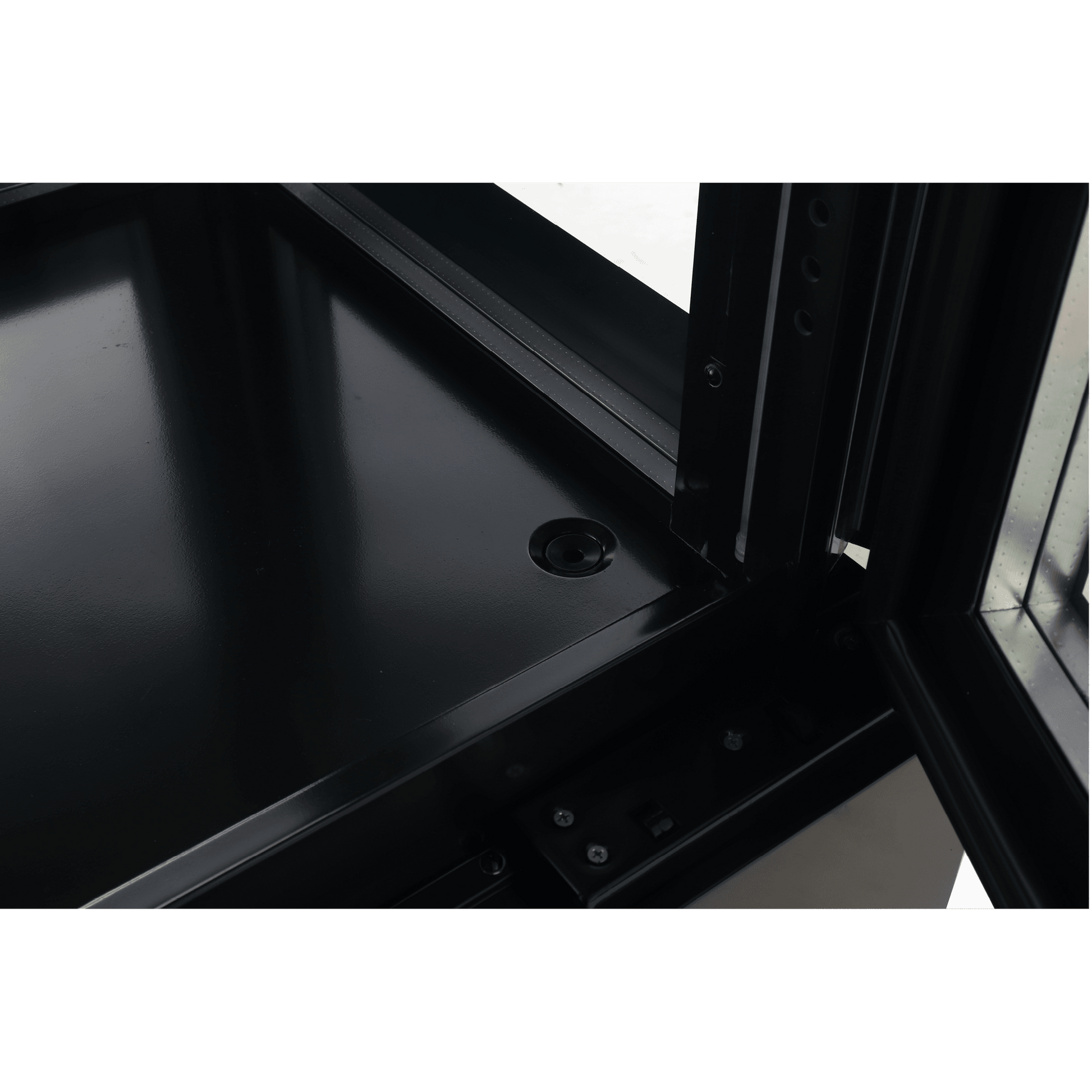 Close-up of black painted steel corner with glass panels and metal framing inside upright display freezer.