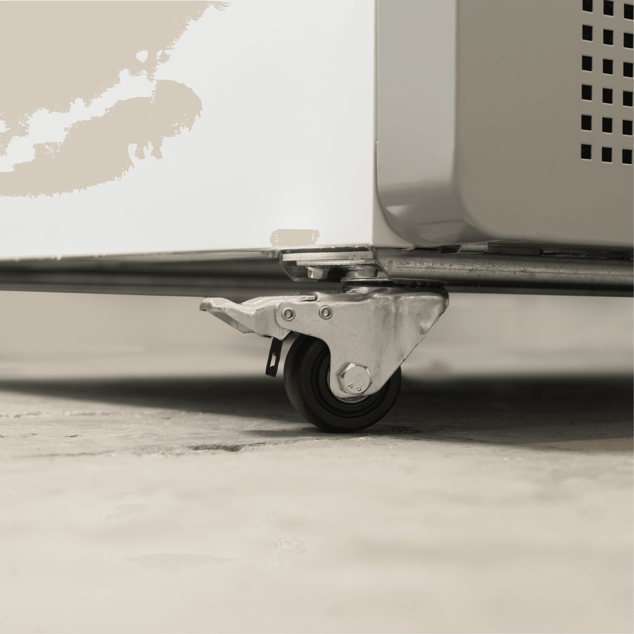 Close-up of metal caster wheel with brake attached to white painted steel base of upright display refrigerator.