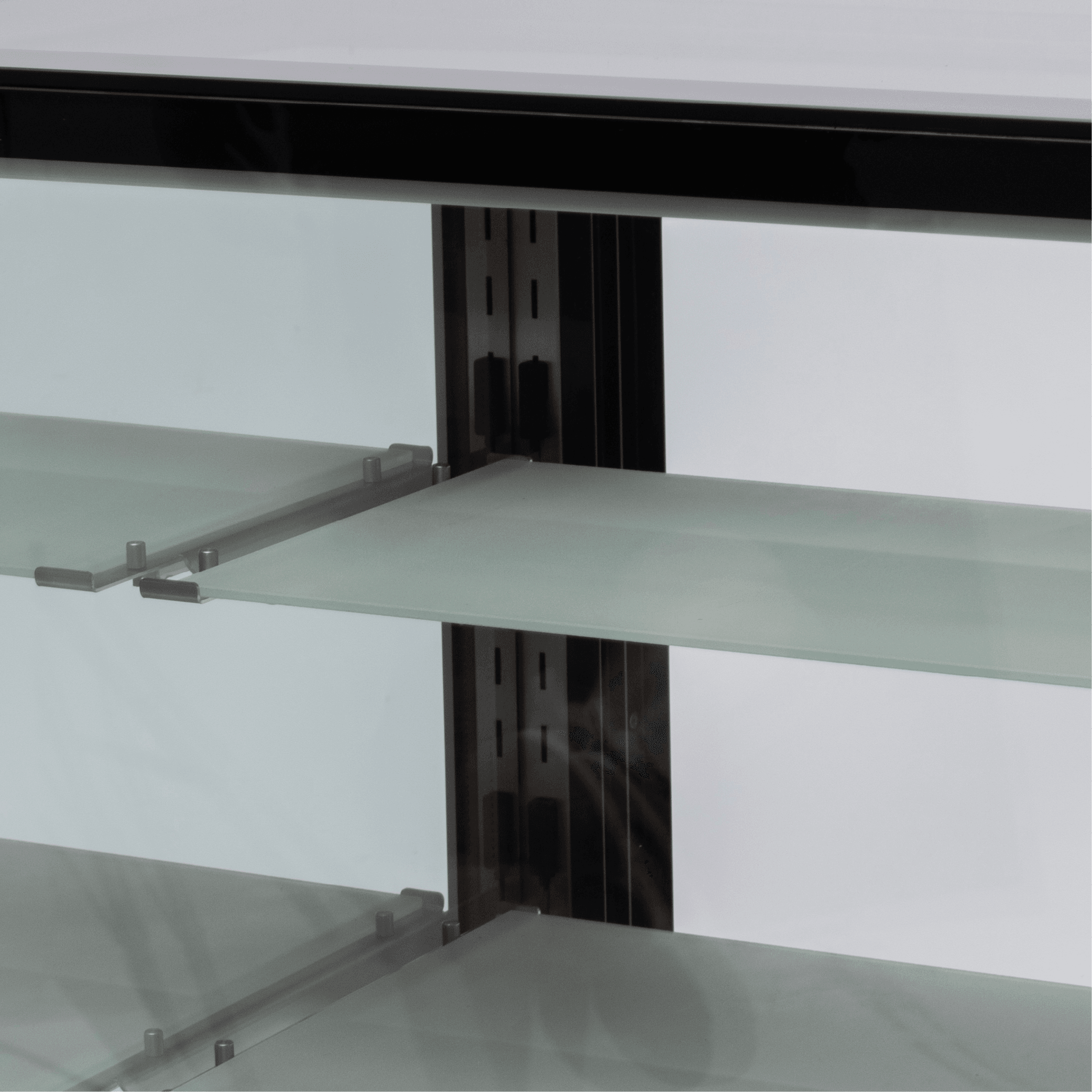 Three-tier glass shelving with black stainless steel frame inside refrigerated cake display unit.