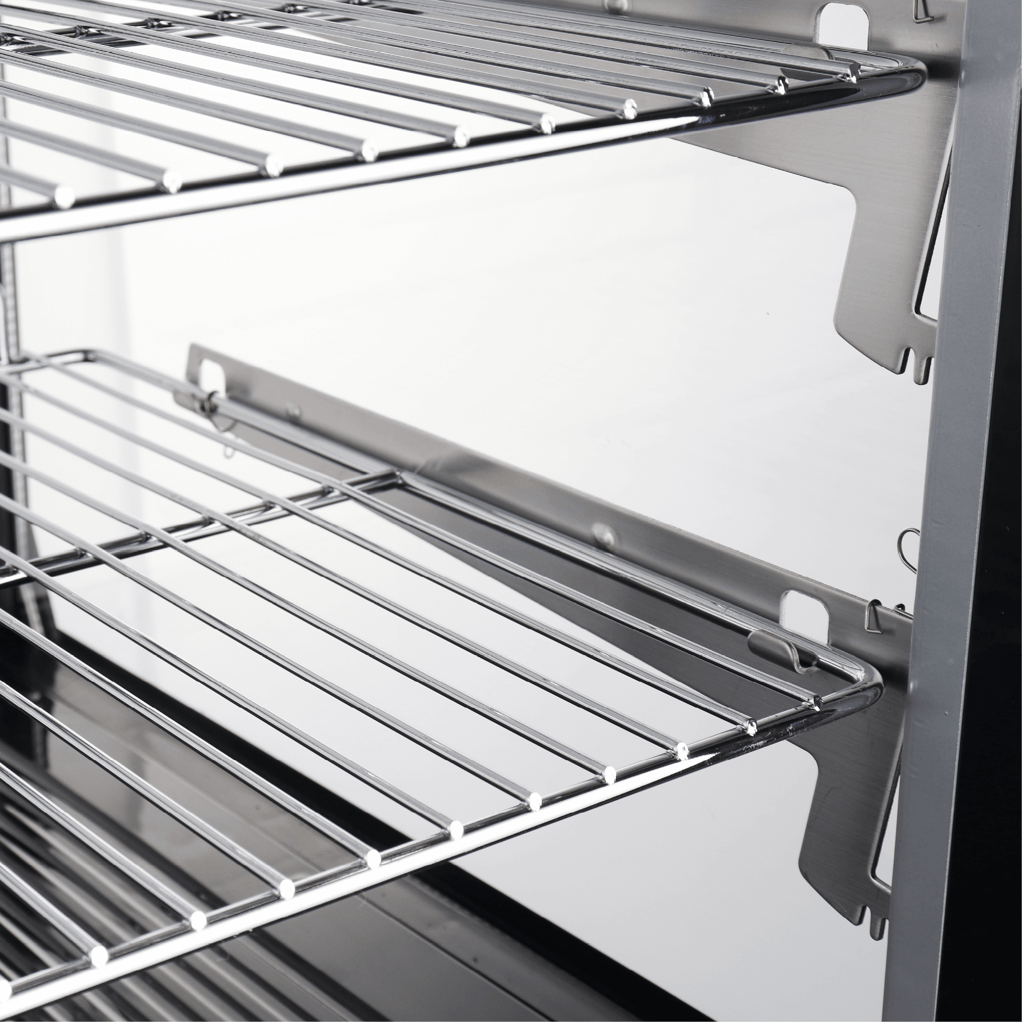 Stainless steel curved interior with wire racks inside a refrigerated cake display unit.