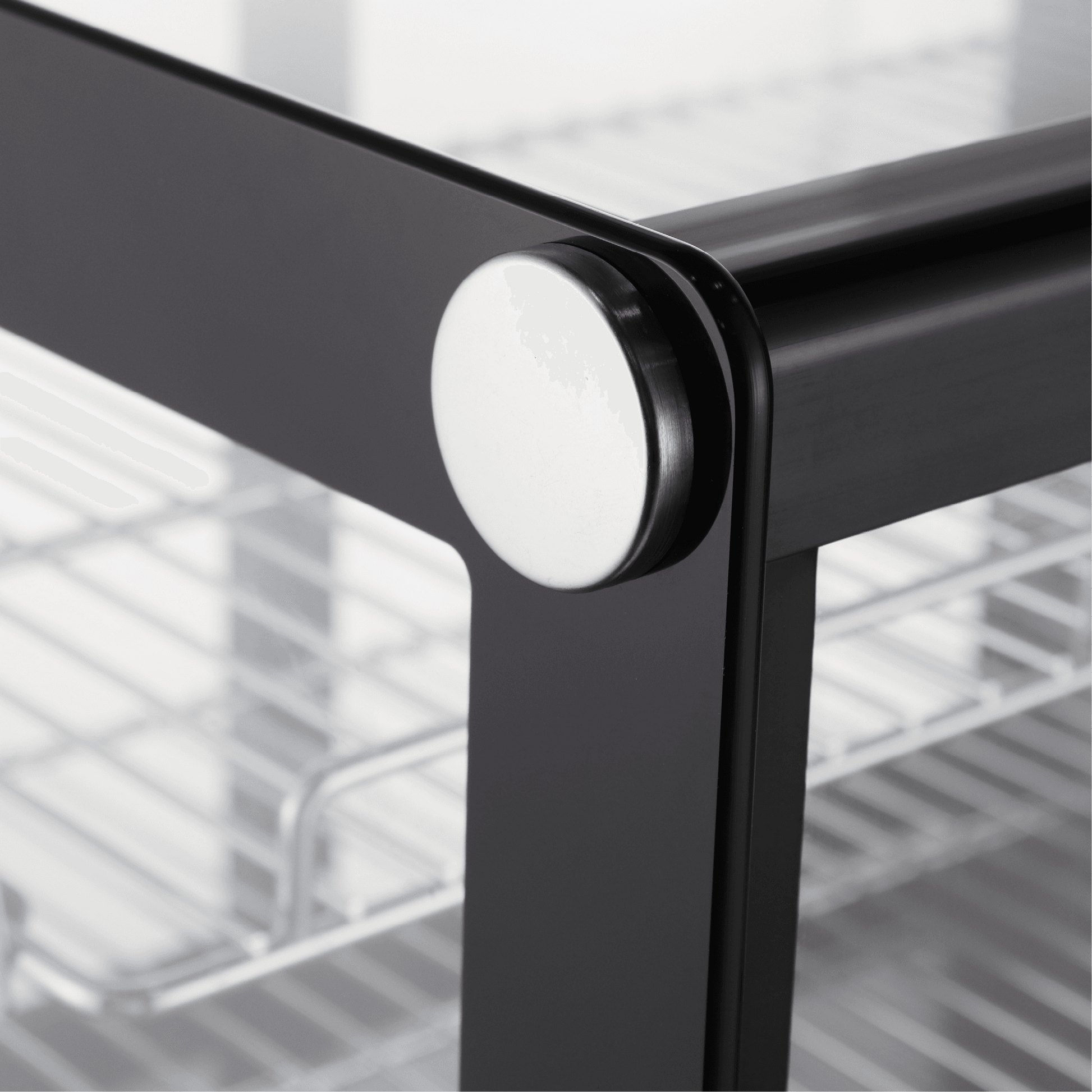 Close-up of black stainless steel frame with curved glass corner on countertop cake display refrigerator.