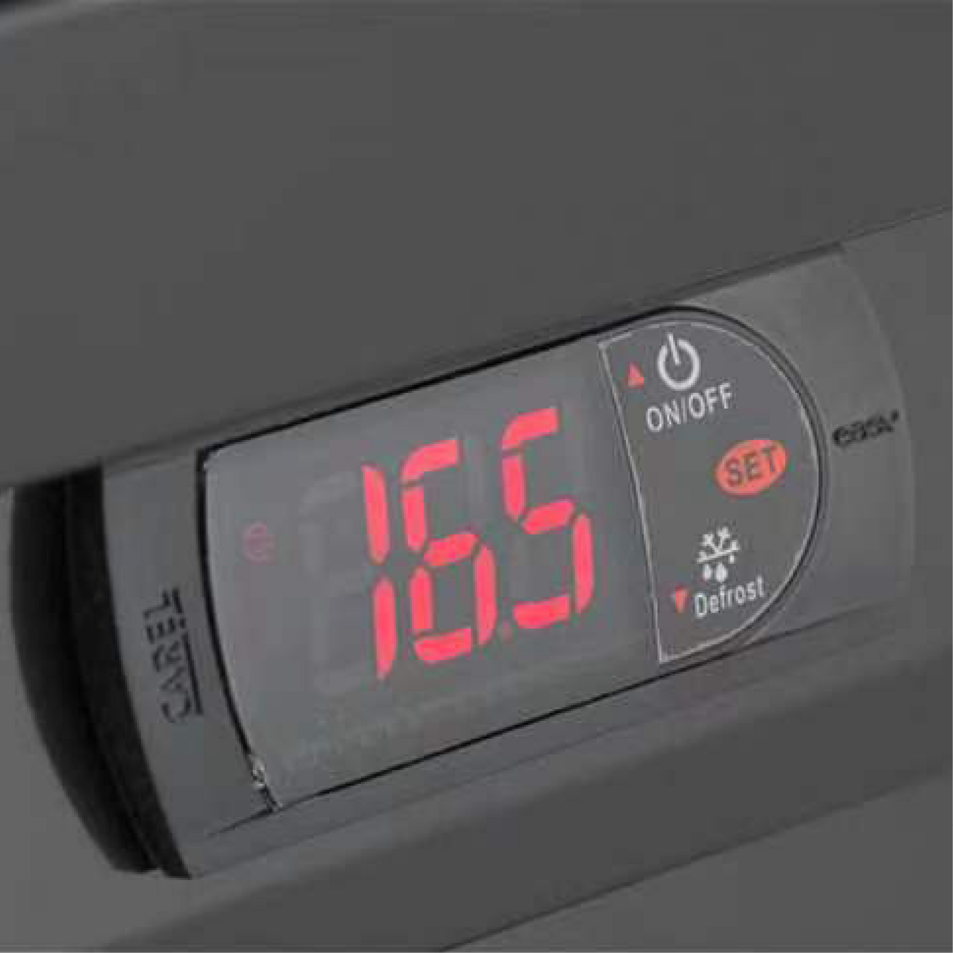 Digital temperature control panel with red LED display and touch buttons on upright white fridge door.