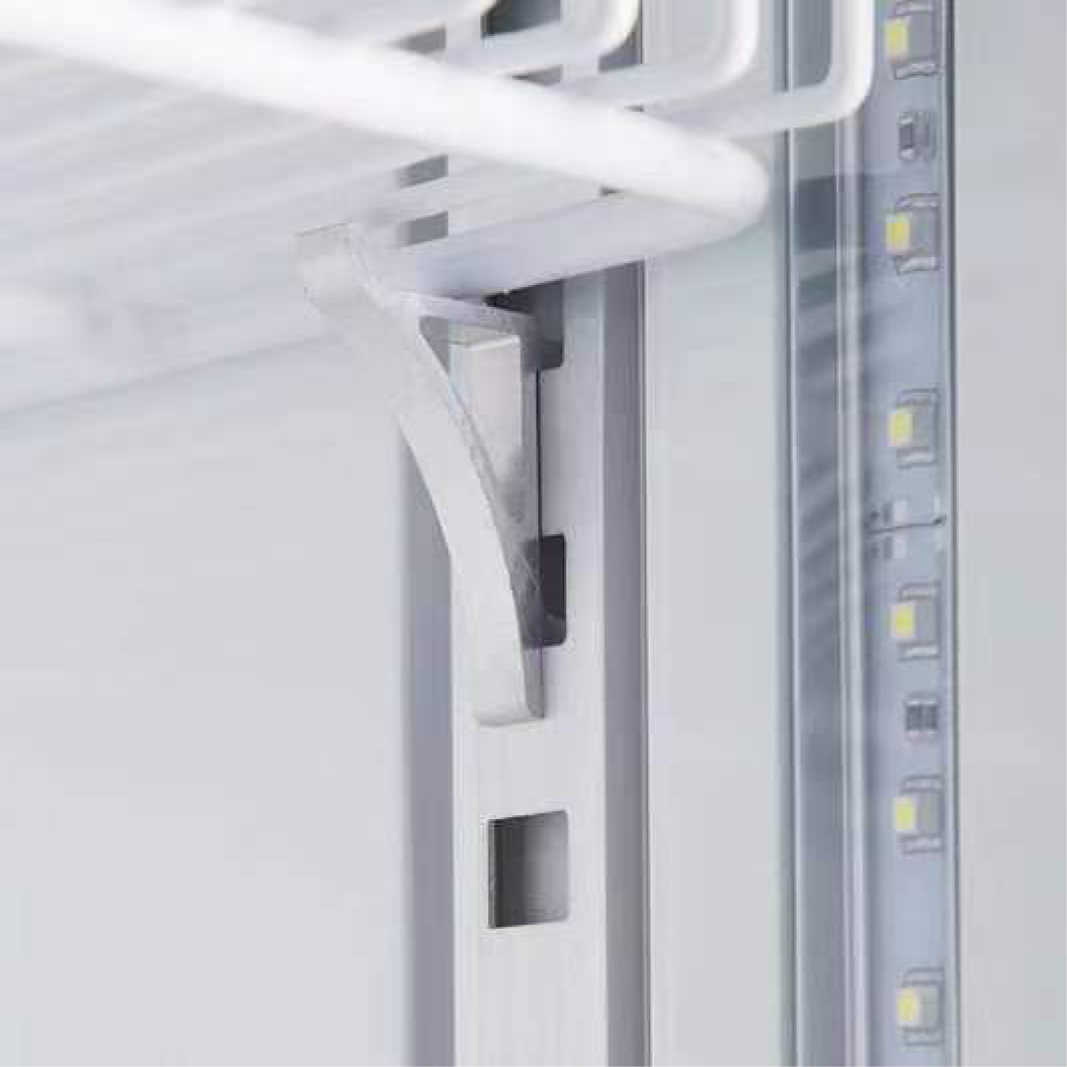 Close-up of white upright display refrigerator door hinge and interior LED light strip on painted steel frame.