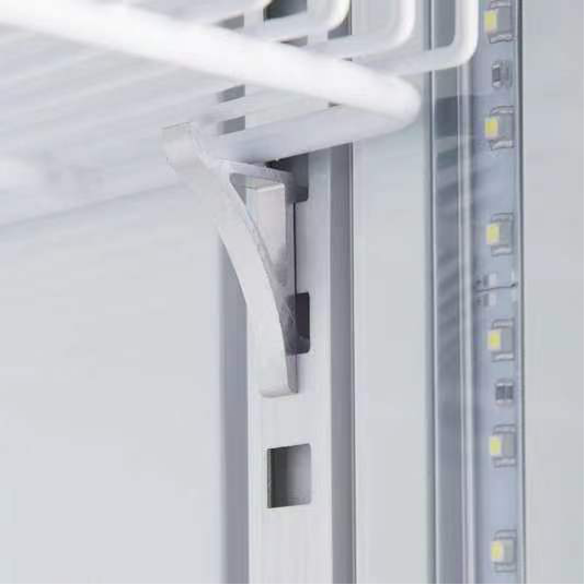 Close-up of white painted steel shelf bracket inside black upright glass door display fridge with LED strip lighting on side