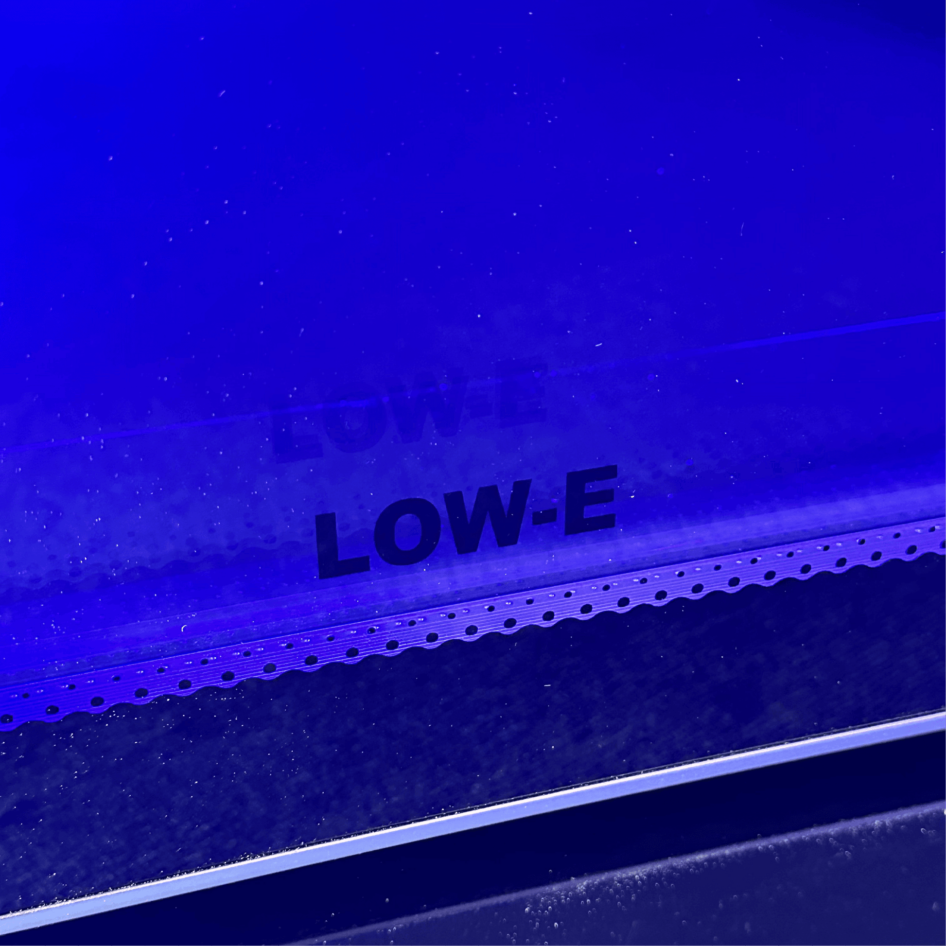 Close-up of low-E tinted glass on black steel frame of upright display refrigerator door.