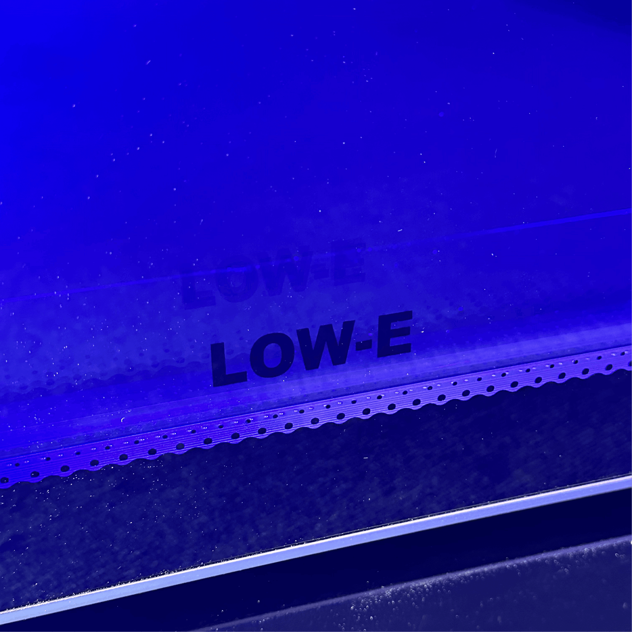 Close-up of low-E tinted glass on black steel frame of upright display refrigerator door.