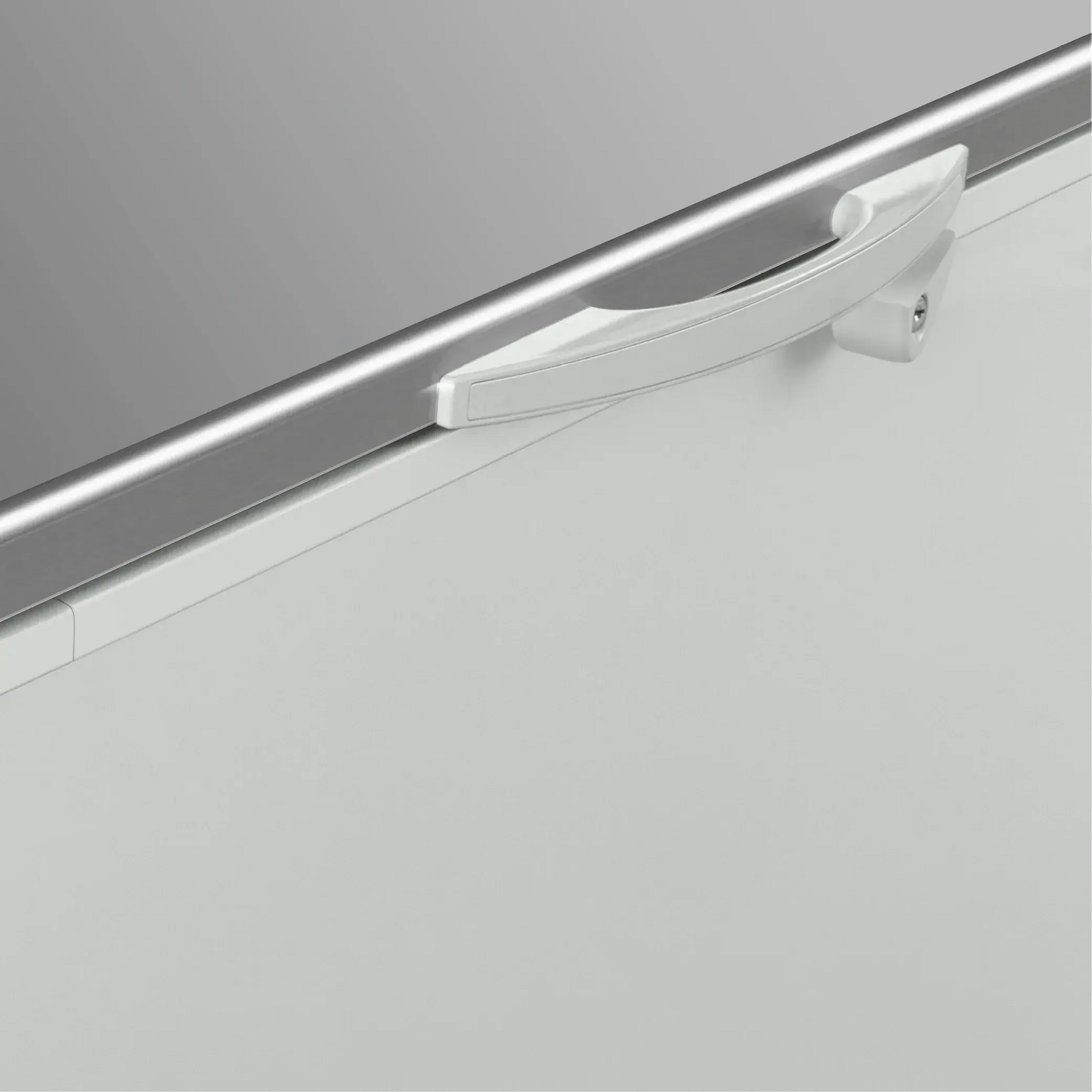 White painted steel chest freezer corner with smooth white handle and stainless steel top panel.