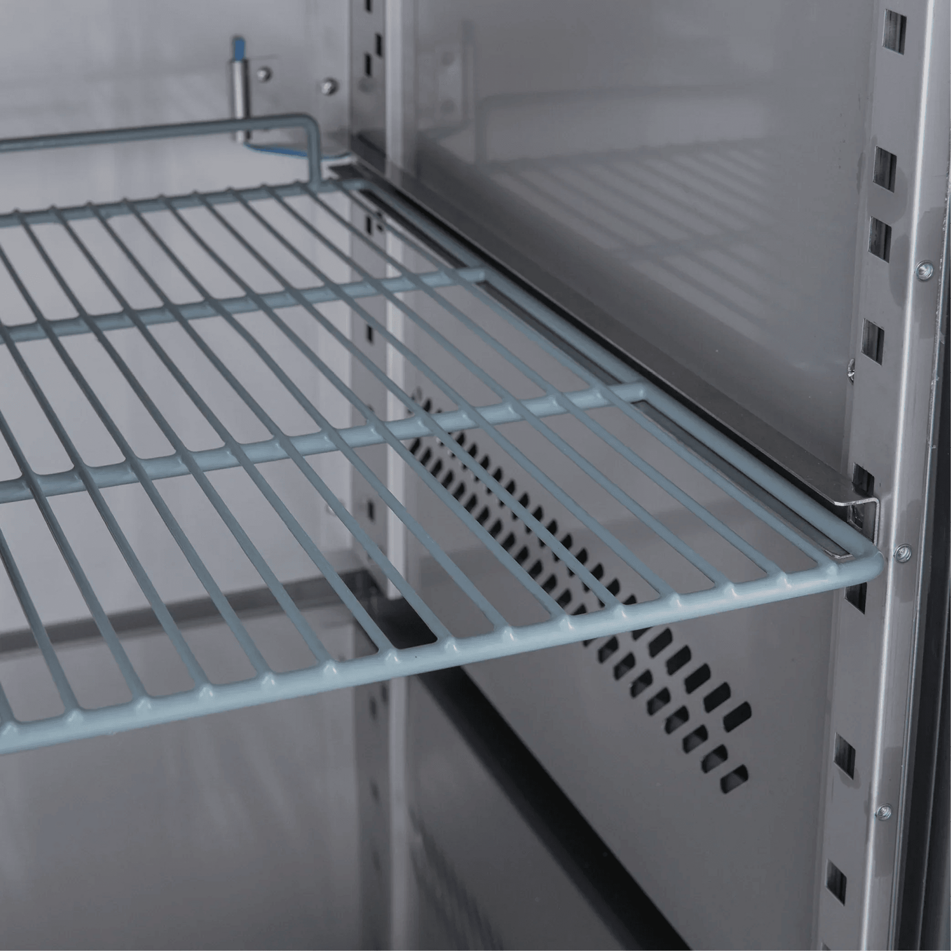 Interior view of stainless steel underbench freezer with adjustable wire shelving and ventilation panel.