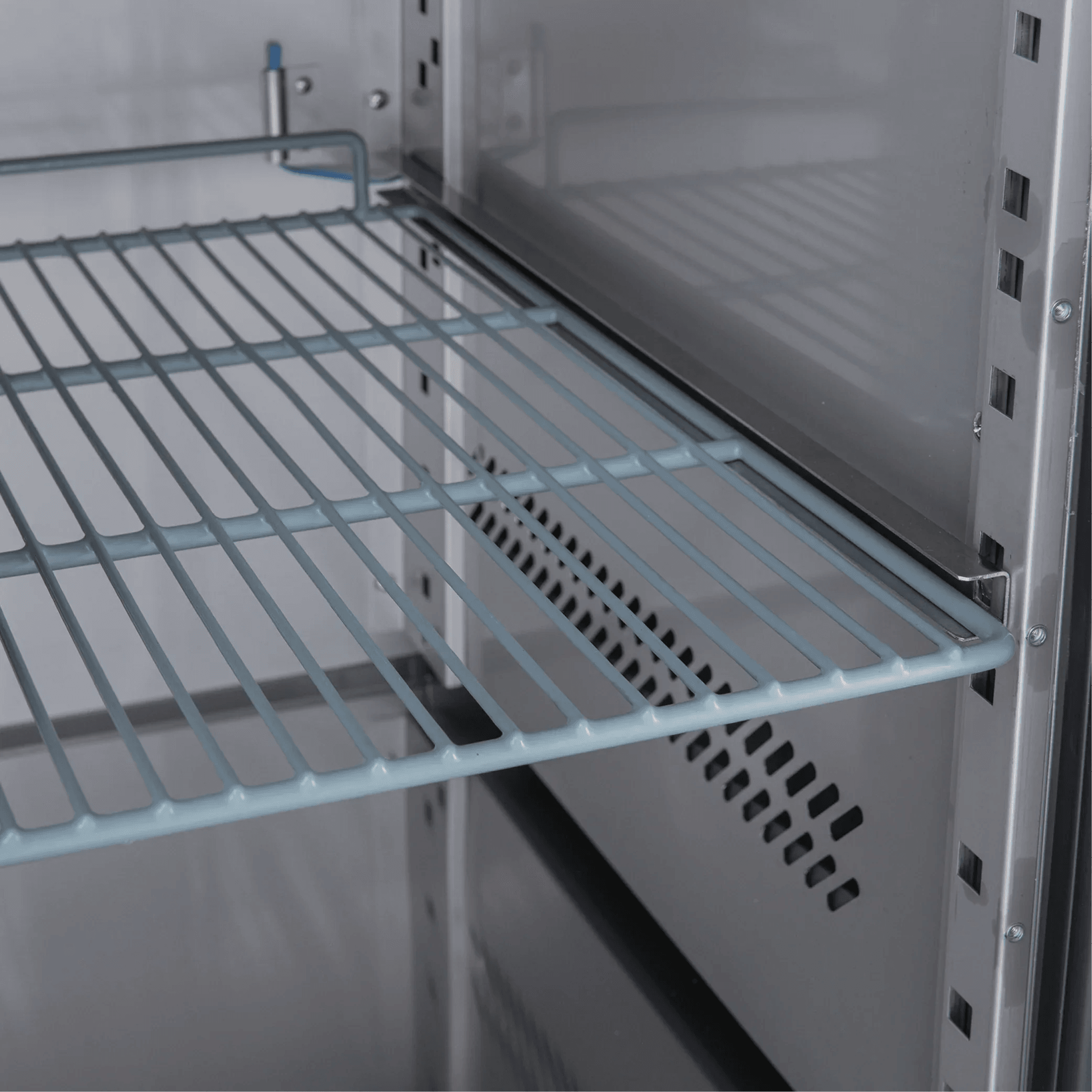 Interior view of stainless steel underbench freezer with adjustable wire shelving and ventilation panel.