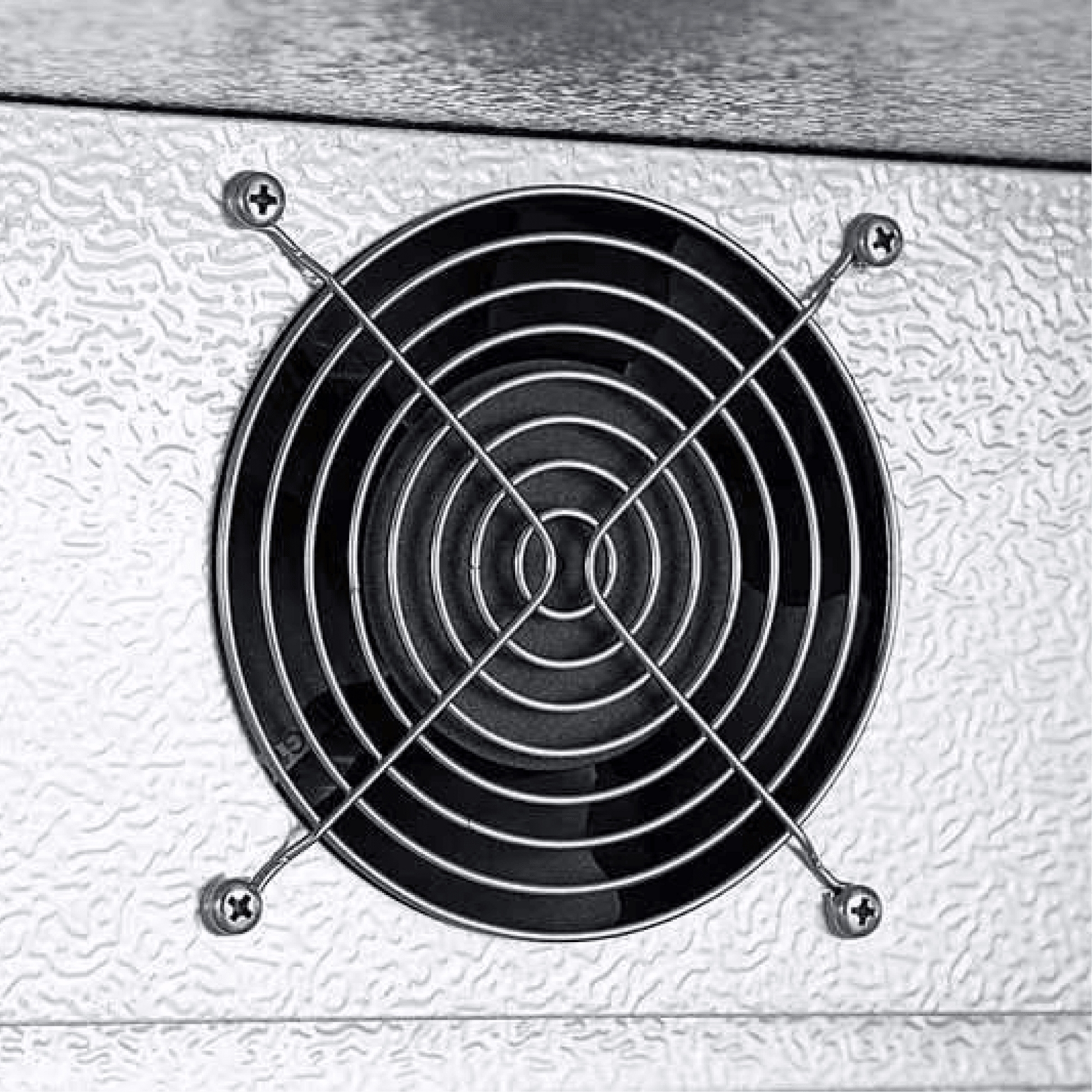 Close-up of textured silver metal surface with circular black ventilation fan grille secured by four screws.
