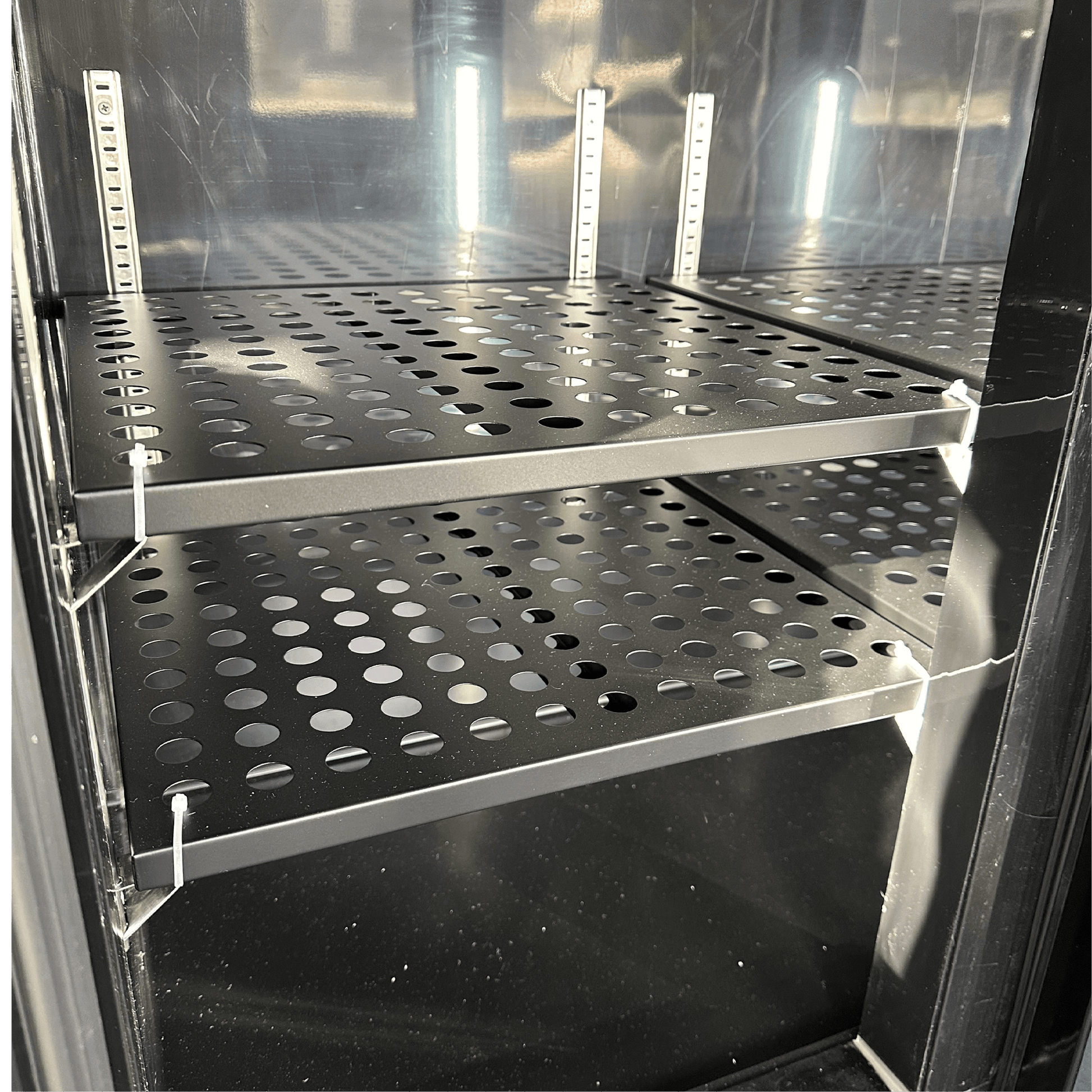 Black steel underbench refrigerator with two glass doors and perforated metal shelves.