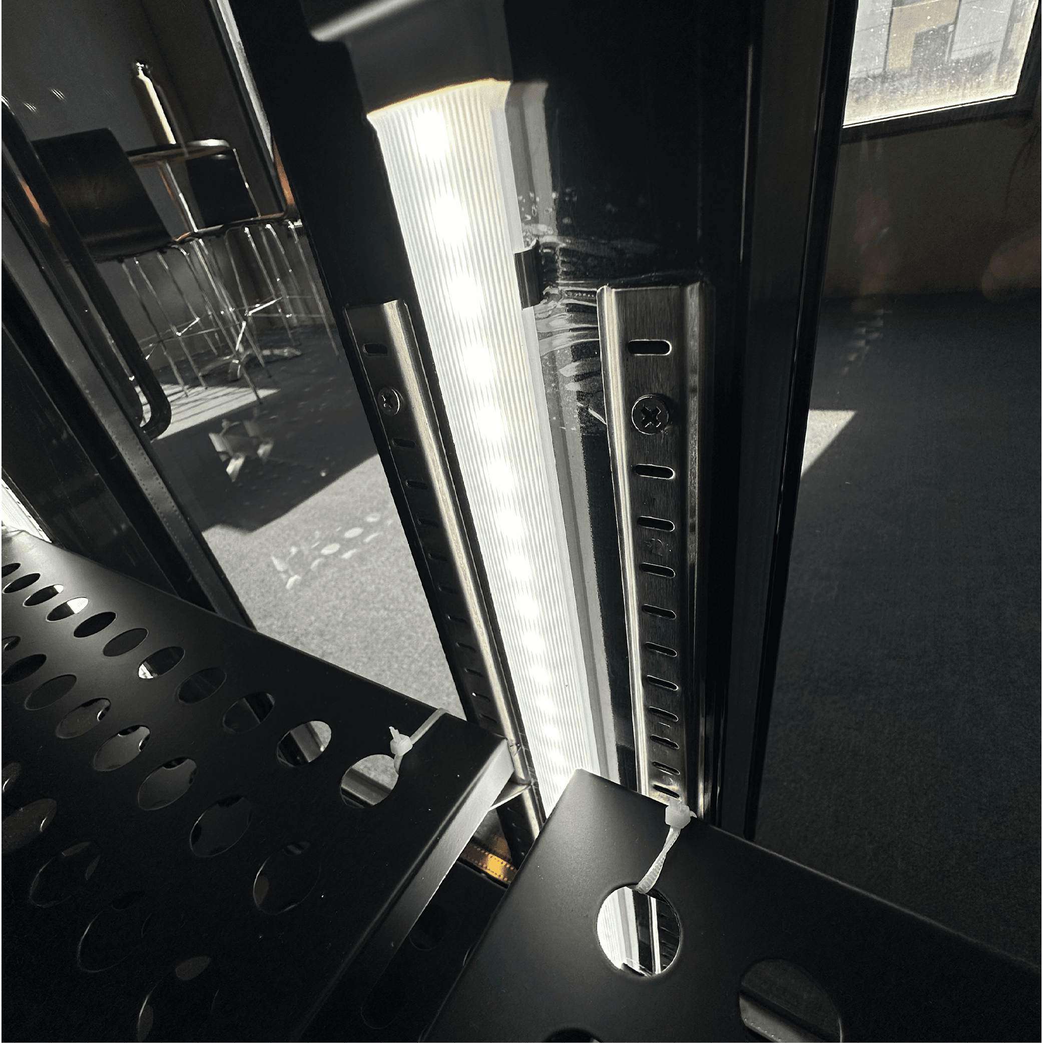 Underbench black glass door refrigerator with LED interior lighting and adjustable steel shelving.