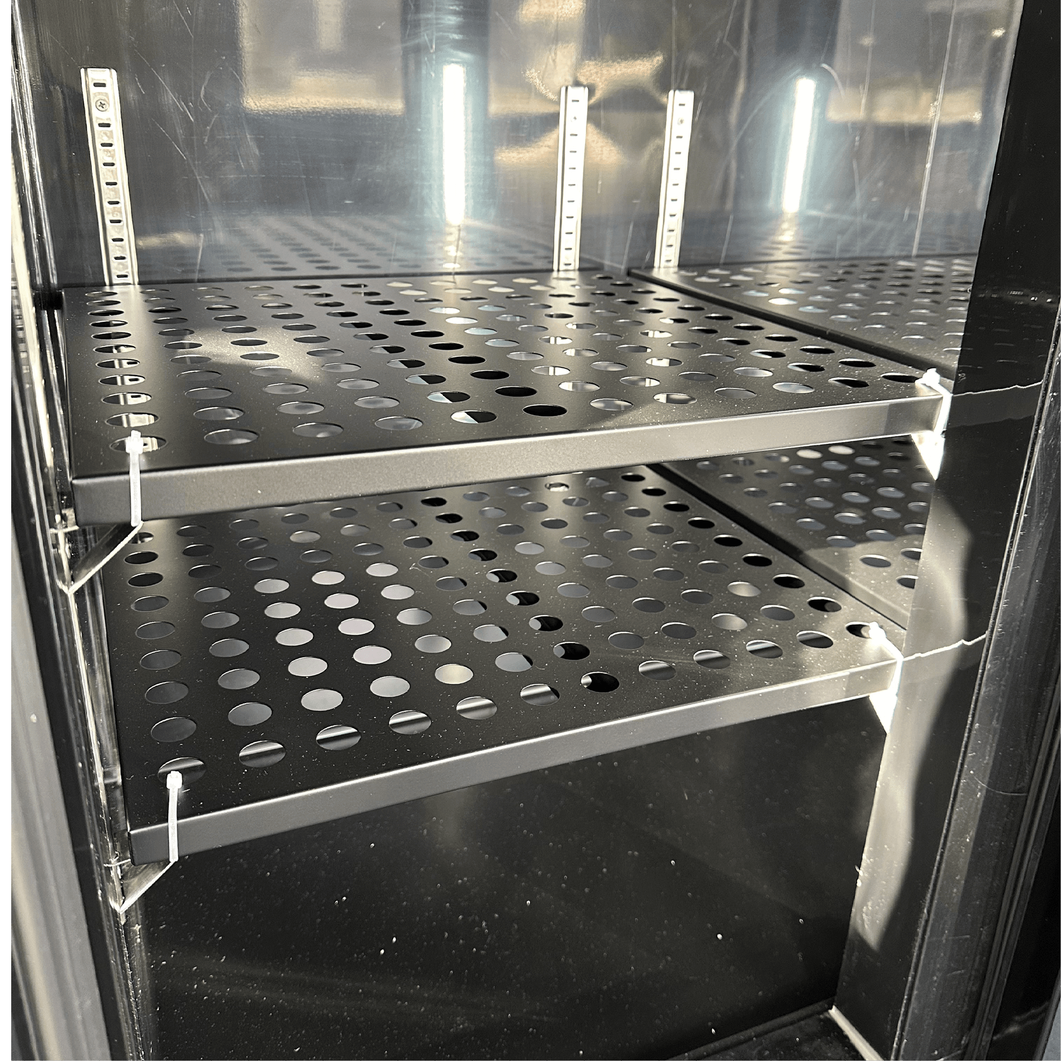 Black underbench refrigerator with perforated metal shelves and glass door panel.