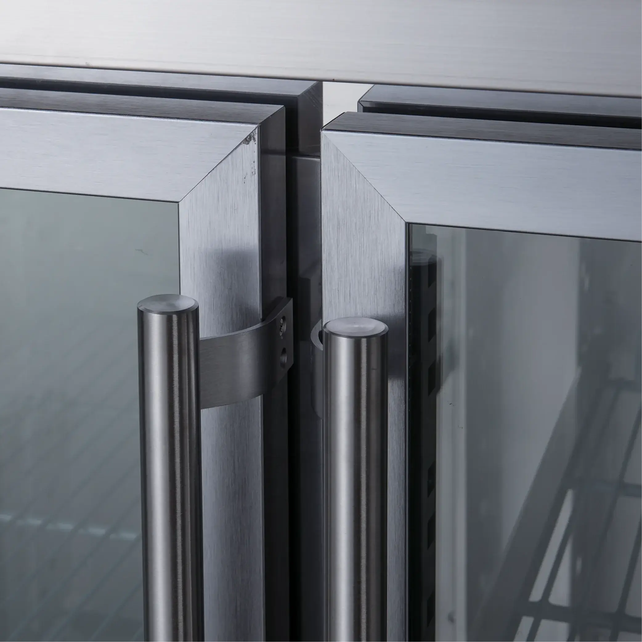 Close-up of stainless steel underbench refrigerator with three glass doors and vertical handles.