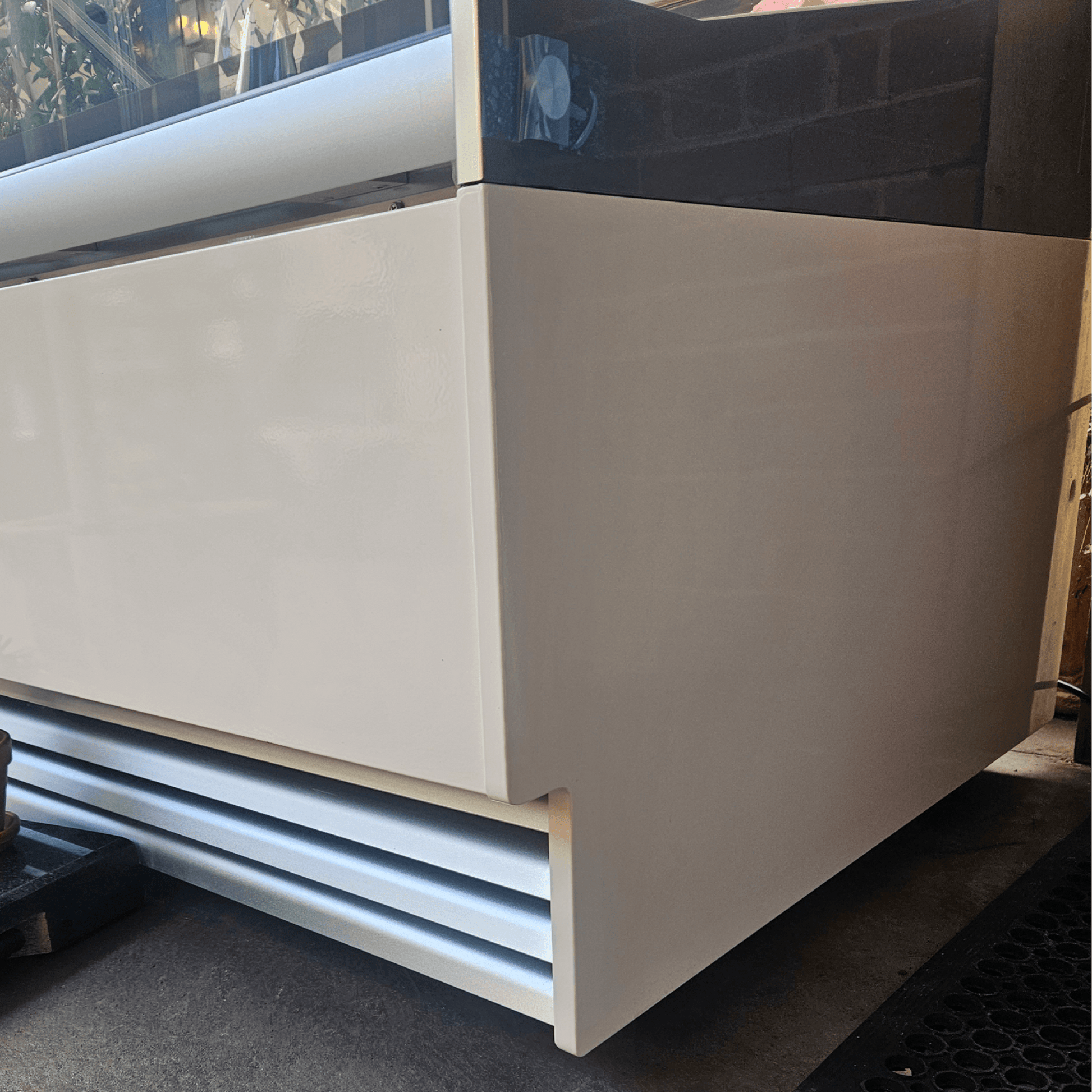 White painted steel and glass ice cream scooping freezer with 16 tub slots and vented base panel.