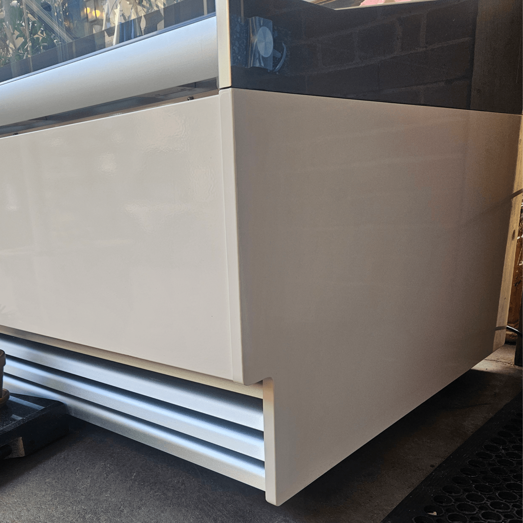 White rectangular commercial freezer with smooth painted steel panels and black tinted glass top display.