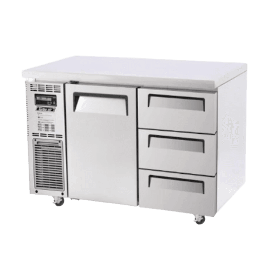 Stainless steel underbench fridge with one door and three drawers, ventilation grille on left side, caster wheels.